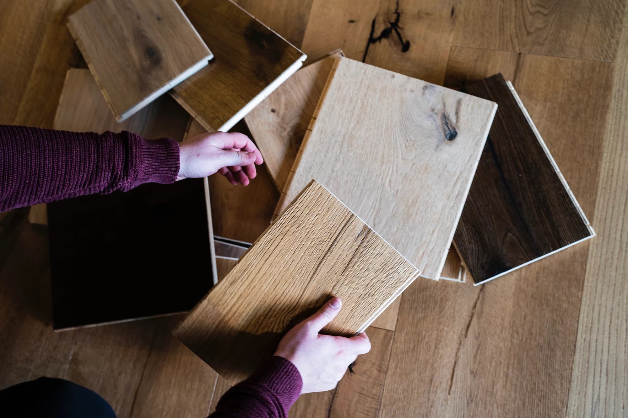 Parquet samples being compared by hand on the floor